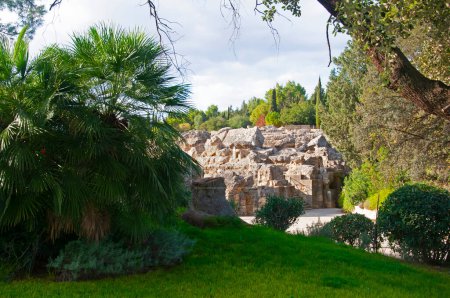 Foto de Antiguos muros romanos en ruinas y árboles verdes en el parque nacional de Sevilla, España - Imagen libre de derechos