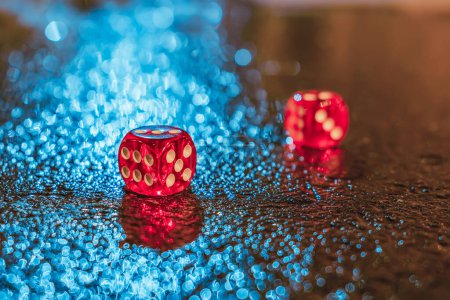 Photo for Red dices lie on the wet, after rain, night asphalt in the light of bright city lights - Royalty Free Image