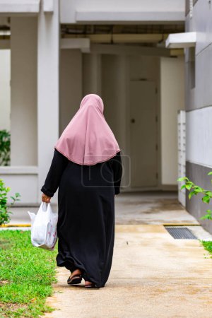 Téléchargez les photos : Vieille femme musulmane dos tourné tout en marchant dans une rue - en image libre de droit