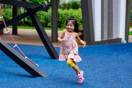 Téléchargez les photos : Mignon petit asiatique gamin fille tout en courant et profiter sur un aire de jeux - en image libre de droit