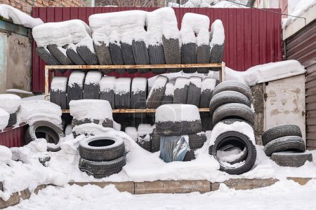 Foto de Pila de desgastados, neumáticos de automóviles usados yacen en la nieve en invierno - Imagen libre de derechos