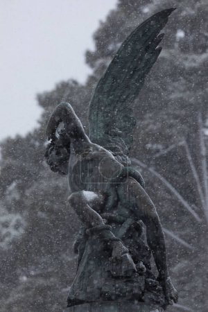 Foto de Escultura de bronce, Fuente Ángel Caído, en un día nevado, Madrid - Imagen libre de derechos