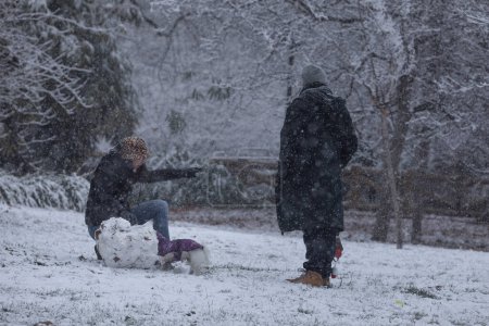 Téléchargez les photos : Les gens profitent d'une journée enneigée dans le parc du Retiro, Madrid - en image libre de droit