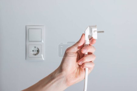 Photo for Energy concept: Plug, ready to connect. White cable and plug socket in the blurry background - Royalty Free Image