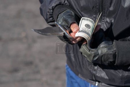 Foto de Manos de bandidos sostienen un cuchillo y cuentan billetes - Imagen libre de derechos