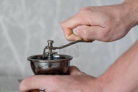 Téléchargez les photos : Machine mécanique pour moudre les grains de café entre les mains d'une personne - en image libre de droit