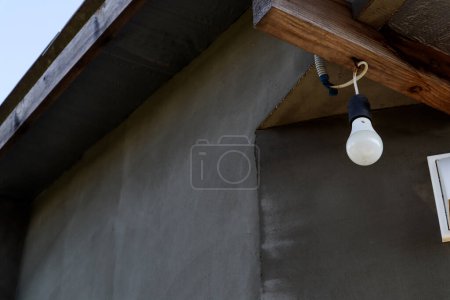 Téléchargez les photos : "Une ampoule blanche pend sur le porche" - en image libre de droit