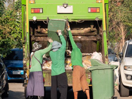 Téléchargez les photos : Service de ramassage des ordures l'équipe de ramassage des ordures pour jeter les déchets dans le camion à ordures - en image libre de droit