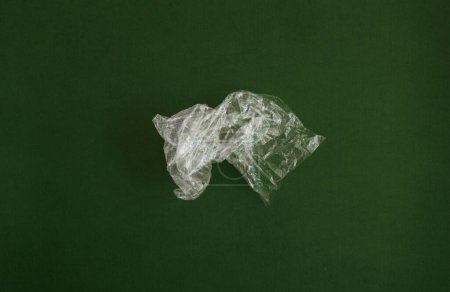 Photo for Crumpled plastic polyethylene bag on a green background. Contamination of the planet. Clear plastic bag. Zero waste concept - Royalty Free Image