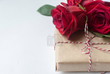 Photo for "Composition of gift and bouquet of red roses on white background . Happy Valentines Day. Top view. Space for text." - Royalty Free Image