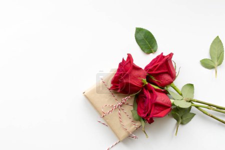 Photo for "Composition of gift and bouquet of red roses on white background . Happy Valentines Day. Top view. Copyspace" - Royalty Free Image