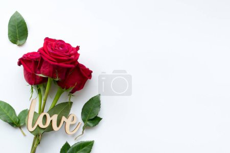 Photo for "Composition of bouquet of red roses and decorative wooden word love on white background . Happy Valentines Day. Top view. Space for text. Copyspace" - Royalty Free Image