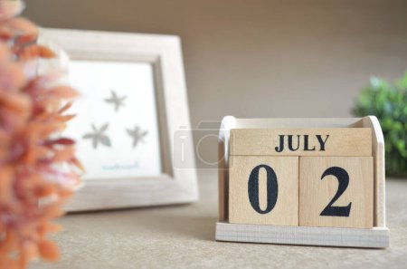 Photo for Wooden calendar with month of July and picture frame - Royalty Free Image