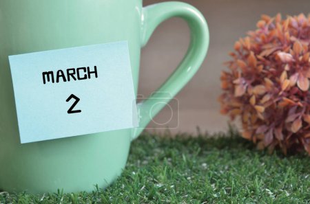 Photo for "close-up shot of cup, sticky note with inscription March 2." - Royalty Free Image