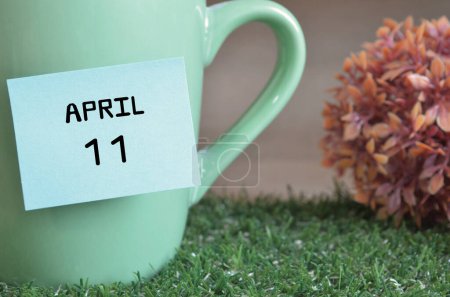 Foto de Taza de color menta con palo de papel y la fecha del mes de abril - Imagen libre de derechos