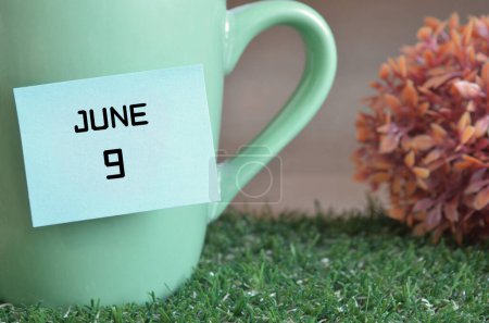 Photo for "close-up shot of cup, sticky note with inscription June 9." - Royalty Free Image