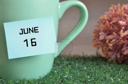 Photo for "close-up shot of cup, sticky note with inscription June 16." - Royalty Free Image