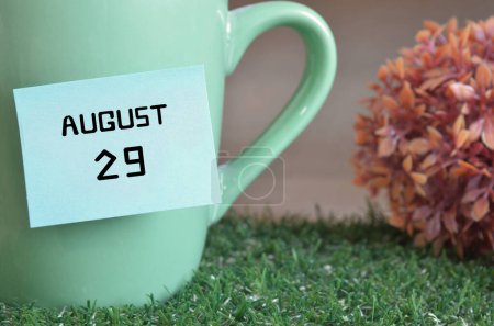 Photo for "close-up shot of cup, sticky note with inscription August 29." - Royalty Free Image