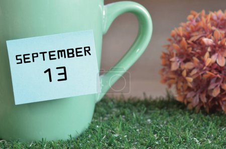 Photo for "close-up shot of cup, sticky note with inscription September 13" - Royalty Free Image