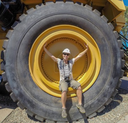 Photo for Tire of a earth moving dump truck with a man in the wheel for scale in australia - Royalty Free Image