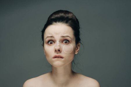 Téléchargez les photos : Frightened woman's face naked shoulders hairstyle gray background model - en image libre de droit
