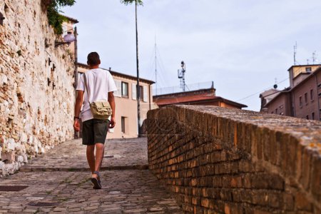 Téléchargez les photos : Vue arrière d'un touriste homme marchant dans la ville antique
. - en image libre de droit