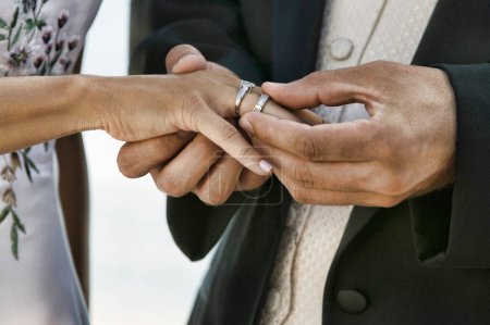 Photo for Groom Putting Ring on Bride's Finger - Royalty Free Image