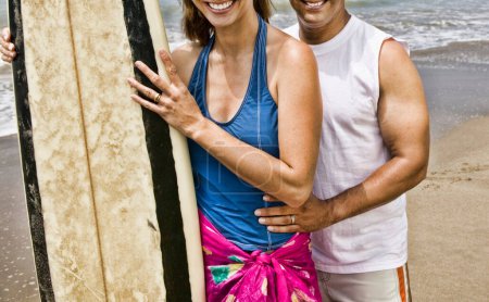 Photo for Couple on the beach holding surfing board - Royalty Free Image