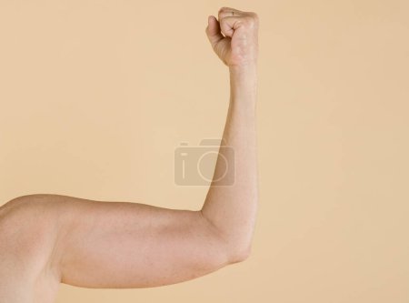 Photo for Young man showing strength in biceps, muscles. - Royalty Free Image