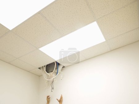 Téléchargez les photos : Mains atteignant vers le câble suspendu au trou dans le plafond - en image libre de droit