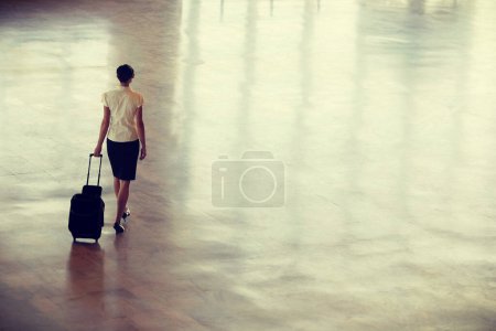 Foto de Joven mujer de negocios caminando en el aeropuerto con la maleta - Imagen libre de derechos