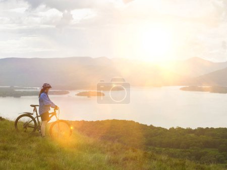 Foto de Mujer joven en bicicleta cerca de hermoso lago - Imagen libre de derechos