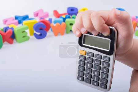 Foto de Pequeña calculadora en la mano con letras coloridas detrás - Imagen libre de derechos