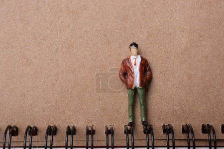Photo for The figurine of a little man standing beside spiral notebook - Royalty Free Image