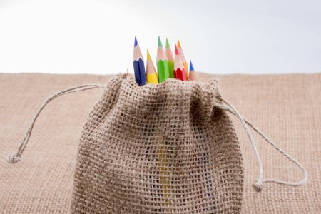 Foto de Lápices de color en saco de lino sobre tela - Imagen libre de derechos