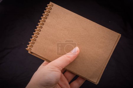 Foto de Notebook  in hand on a black color background - Imagen libre de derechos