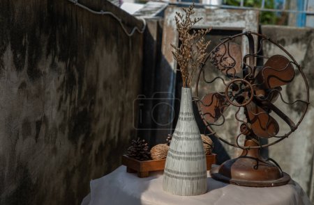 Foto de "Flores secas en jarrón de cerámica sobre tela de mesa texturizada rosa y abanico vintage con pared de cemento viejo. " - Imagen libre de derechos