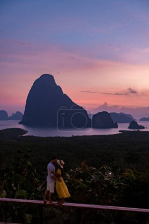 Photo for Couple men and woman mid age watching sunrise in Phangnga bay Thailand, Phanga bay viewpoint, couple watching sunrise on the edge of a swimming pool, infinity pool look out over Phangnga Bay Thailand - Royalty Free Image