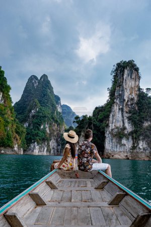 Téléchargez les photos : Couple en bateau à queue longue visitant le parc national de Khao Sok à Phangnga Thaïlande, parc national de Khao Sok avec bateau à queue longue pour les voyageurs, lac Cheow Lan, barrage de Ratchaphapha - en image libre de droit