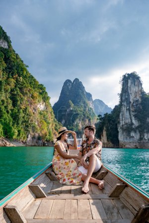 Téléchargez les photos : Couple en bateau à queue longue visitant le parc national de Khao Sok à Phangnga Thaïlande, parc national de Khao Sok avec bateau à queue longue pour les voyageurs, lac Cheow Lan, barrage de Ratchaphapha - en image libre de droit