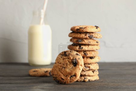 Téléchargez les photos : "Savoureux biscuits aux pépites de chocolat et bouteille de lait sur une table en bois
" - en image libre de droit