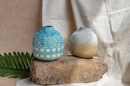 Téléchargez les photos : "Deux vases en céramique faits à la main sur nappe texturée blanche. " - en image libre de droit