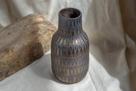 Téléchargez les photos : "Vase en céramique couleur cuivre fait à la main sur nappe texturée blanche. " - en image libre de droit