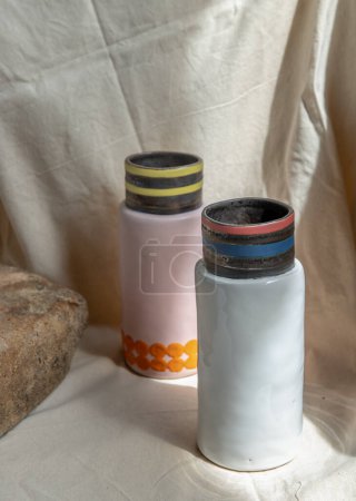Téléchargez les photos : "Deux vases en céramique faits à la main rose et blanc sur nappe texturée blanche. " - en image libre de droit