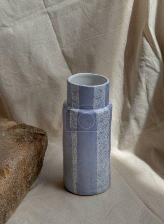 Foto de "Jarrón de cerámica hecho a mano azul sobre manteles texturizados blancos." - Imagen libre de derechos