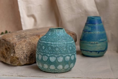 Foto de "Dos jarrones de cerámica hechos a mano azules sobre manteles texturizados blancos. " - Imagen libre de derechos