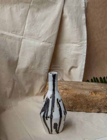 Foto de "Jarrón de cerámica hecho a mano blanco y negro sobre manteles texturizados blancos." - Imagen libre de derechos