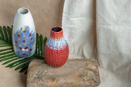 Téléchargez les photos : "Deux vases en céramique faits à la main bleu et rouge sur nappe texturée blanche. " - en image libre de droit