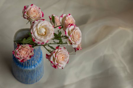 Téléchargez les photos : "Bouquet of flower in Blue handmade ceramic vase on Blush textured table cloth." - en image libre de droit