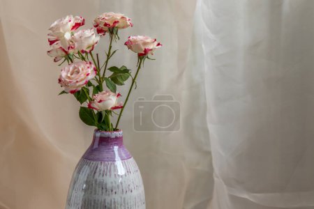 Téléchargez les photos : "Gros plan sur Bouquet de fleurs en vase en céramique violet et blanc fait main sur nappe texturée Blush." - en image libre de droit